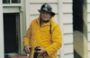 Long-time member and OIC of the Unit, Captain (later Divisional Officer) Dick Reid in typical stance and working uniform at a house fire in Grey Lynn.